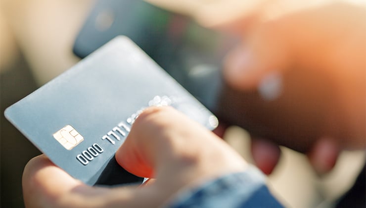 person holding credit card and phone